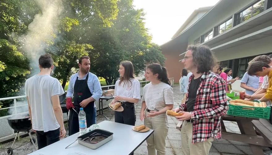Un groupe de 5 personnes sur une terrasse discutant autour d'un barbecue