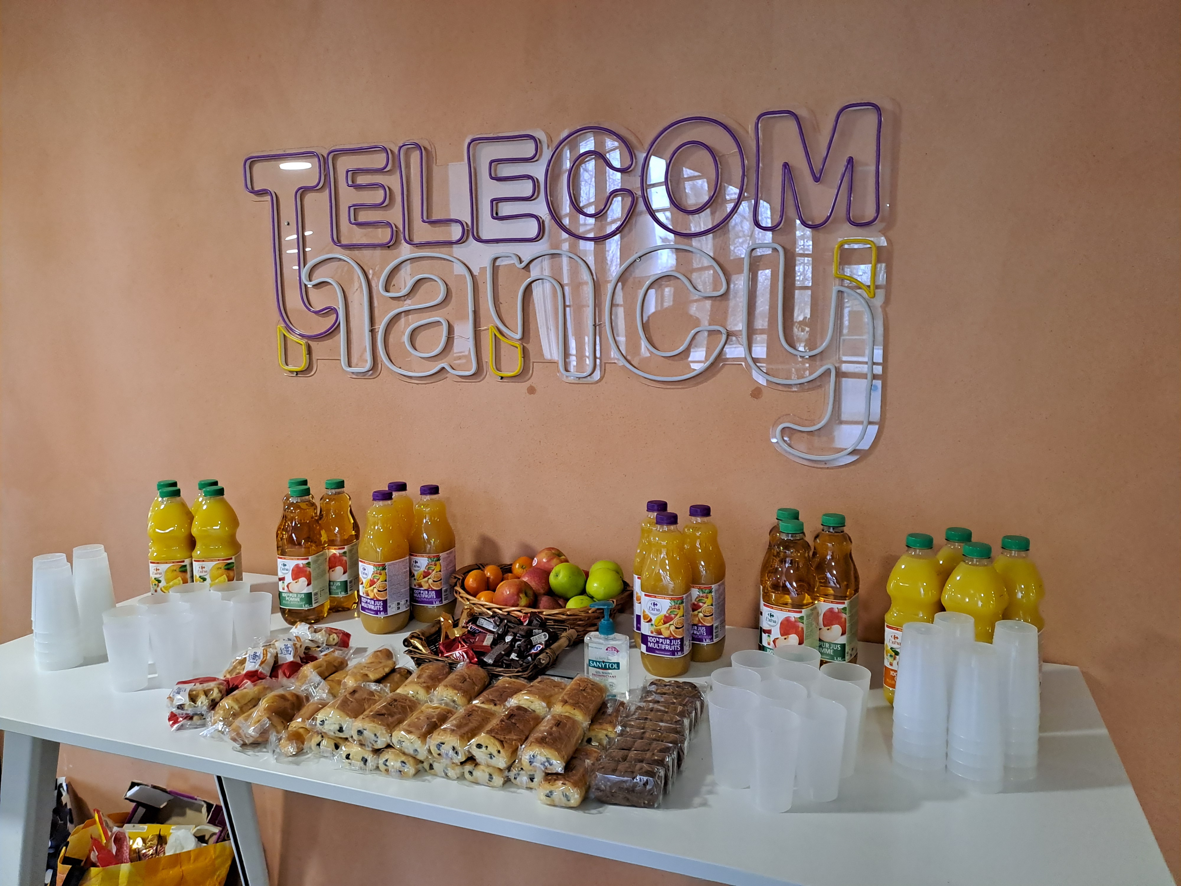 Une table de collations devant un mur affichant le logo de TELECOM Nancy