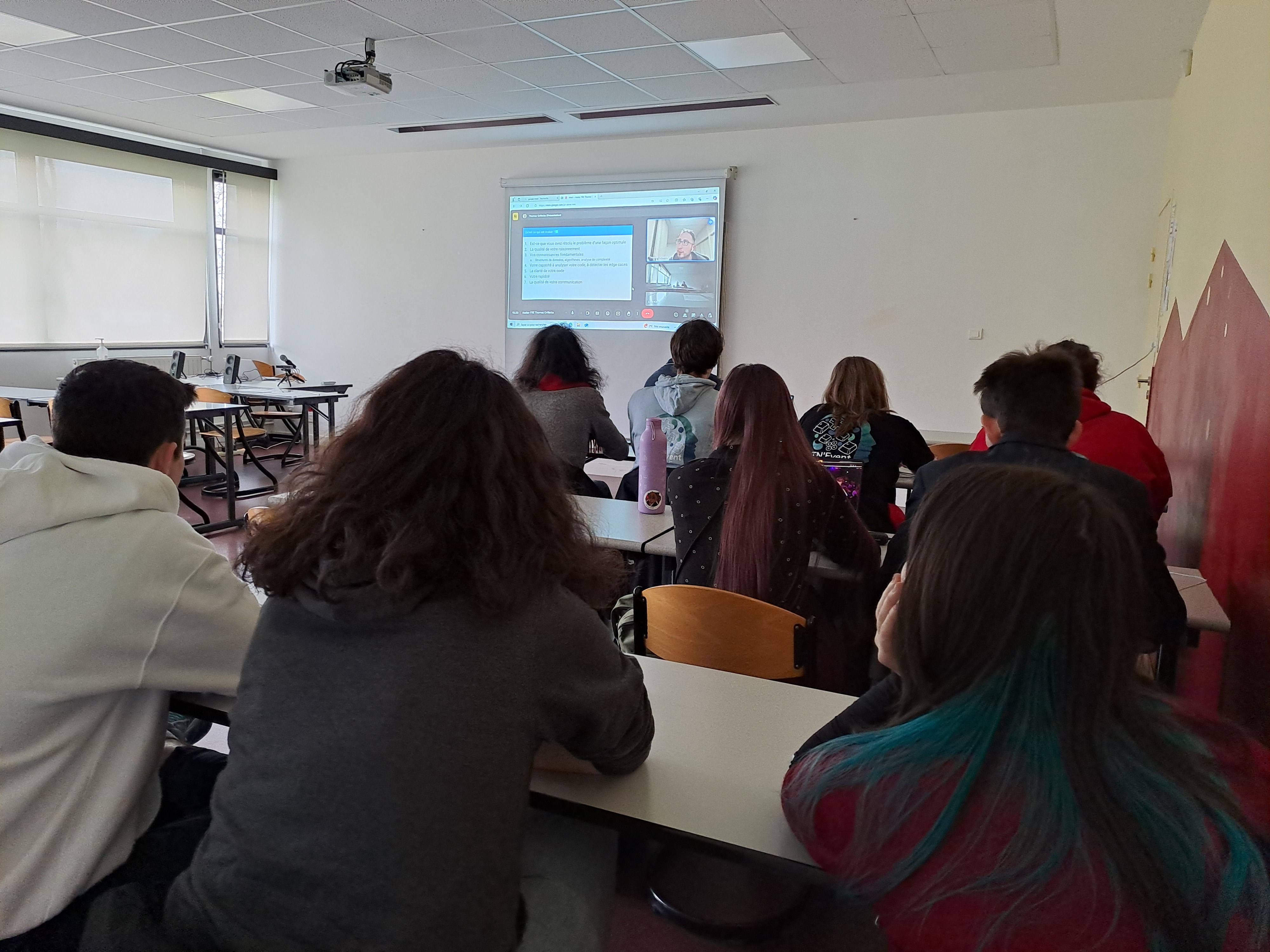 Un groupe de 9 étudiants échange avec un intervenant en visioconférence